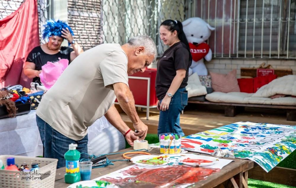 מבוגרים וילדים יוצרים סביב שולחן צבעים
