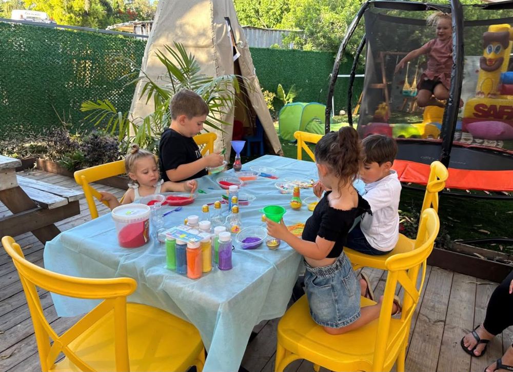 ילדים חוגגים סביב שולחן בבית שי